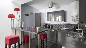 Une cuisine moderne dotée d’un îlot central, de tabourets de bar, d’un réfrigérateur et d’un évier.