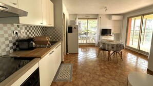 A compact kitchen with a microwave, stove, and checkered backsplash. A dining area with a table and chairs is visible through an open door. - Holiday rental, 2-bedroom apartment for 4 people, on the port of Hyères (HYERES PLAGE)