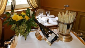 A dining table with a bottle of wine, a vase of flowers, and a basket of asparagus. - Manoir de Contres (Le Controis en Sologne)