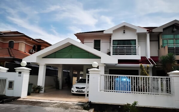 A two-story house with a covered driveway and a white fence.