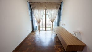 A room with a wooden parquet floor, a long wooden bench, and a window with sheer curtains. - Natol Homestay - Sydney Batu Kawa MJC New Townships (Kuching)
