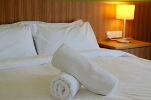 Restful retreat with a neatly made bed, wooden headboard, and a convenient nightstand with a lamp.