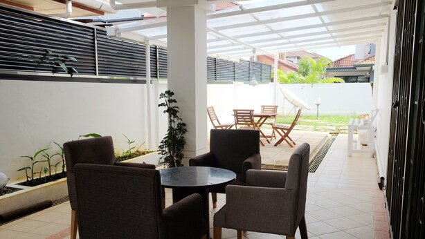 A covered patio area with a round table and four chairs, surrounded by a white wall and a black fence. - Natol Homestay - Sydney Batu Kawa MJC New Townships (Kuching)