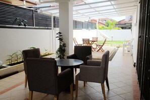 Relax in this serene outdoor seating area with a round table and four chairs, surrounded by a potted plant and a white wall.