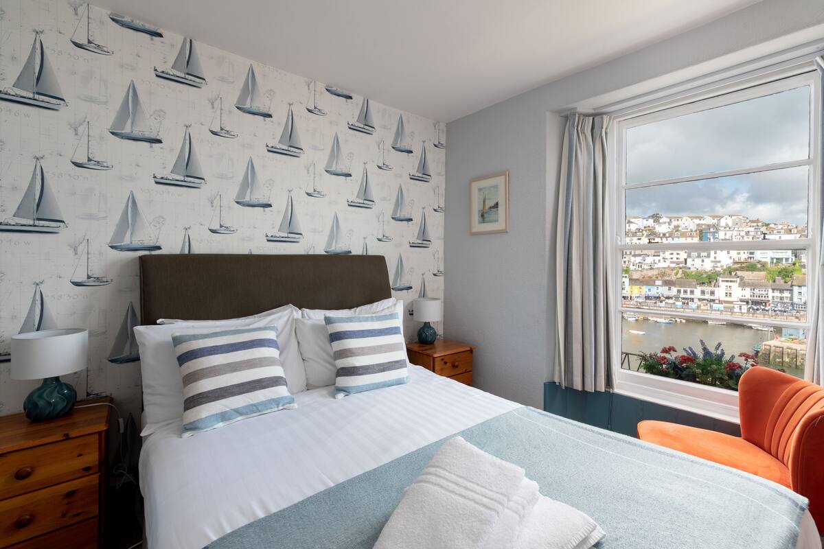 Una habitación de hotel con una cama grande, vistas de la ciudad y una ventana con cortinas.