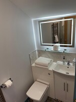 A compact bathroom with a toilet, a sink, a mirror, and a towel rack.