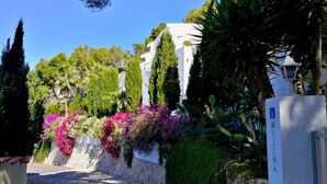 A white building with a stone wall and vibrant flowers. - APARTMENT NEW EXCEPTIONAL VIEW ON A COLINNE FACING THE SEA (a swimming pool) (benissa)