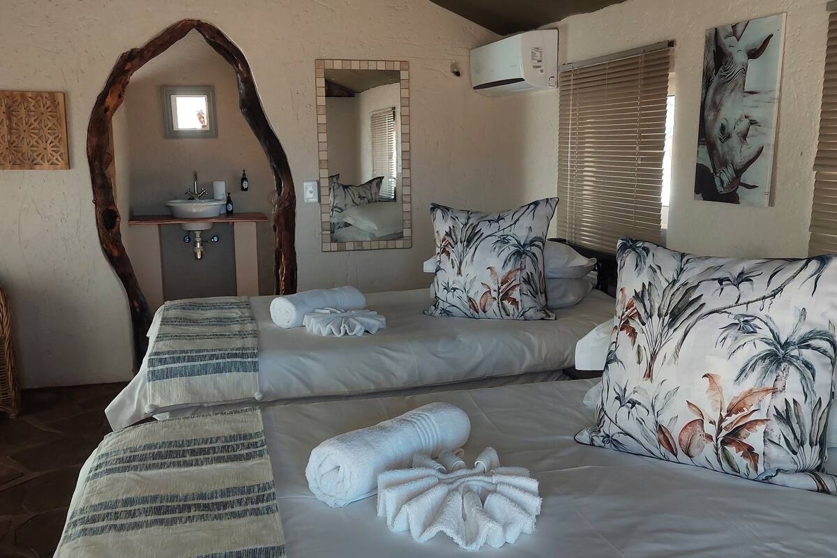 A bedroom with two beds, a bathroom, and a large mirror.