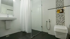 A modern bathroom with a glass shower enclosure, a white sink, and a toilet. - Le Noor (Kanayannur)