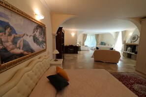 A spacious bedroom with a large bed, a decorative painting, a wooden wardrobe, and a view of the living area. - La cascata negli ulivi (Toscolano Maderno)