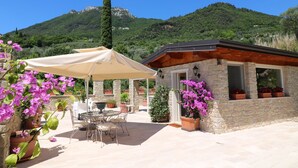 A stone building with a patio area, outdoor seating, and potted plants. - La cascata negli ulivi (Toscolano Maderno)