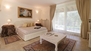A bedroom with a bed, a bedside table, a coffee table, a painting on the wall, and a window with curtains. - La cascata negli ulivi (Toscolano Maderno)