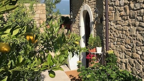 A stone building with a garden featuring lemon trees and potted plants. - La cascata negli ulivi (Toscolano Maderno)