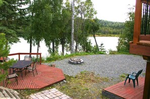 A deck with outdoor seating and a fire pit overlooking a lake. - Kenai Riverfront In Downtown Soldotna (Soldotna)