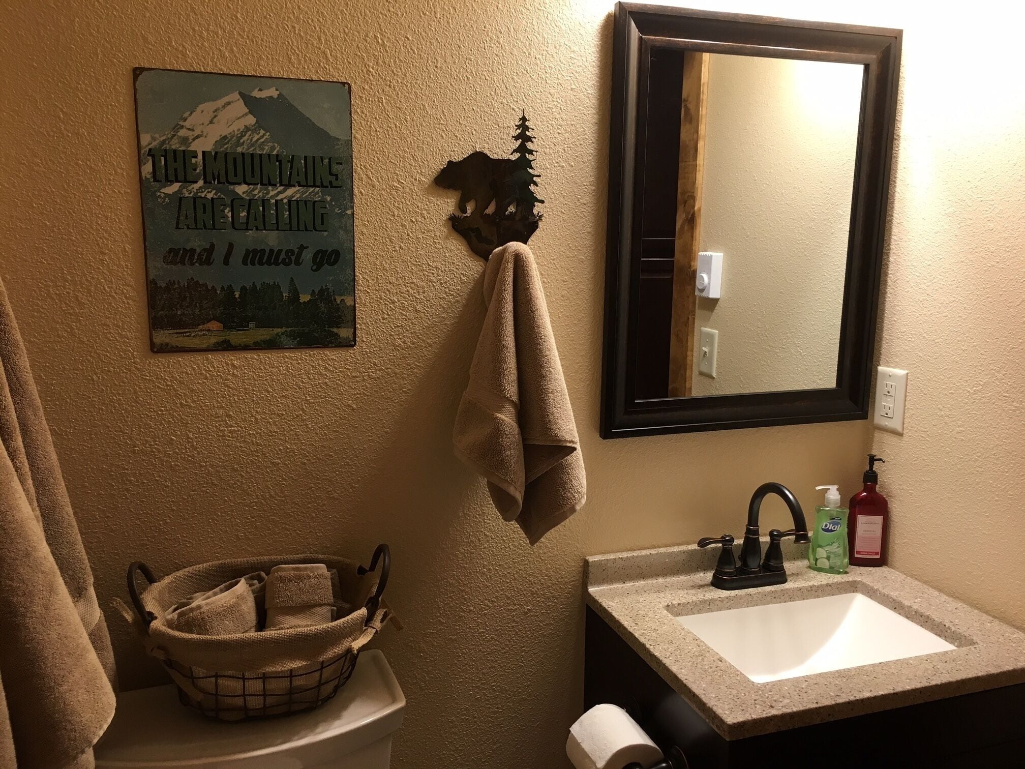 A bathroom with a sink, mirror, towel rack, and a decorative sign.
