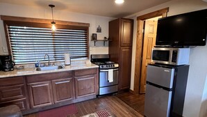Una cucina moderna con mobili in legno, un frigorifero in acciaio inossidabile, un forno a microonde e un piano cottura.
