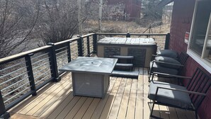 Una terrazza con tavolo e sedie, un barbecue e un edificio rosso sullo sfondo.