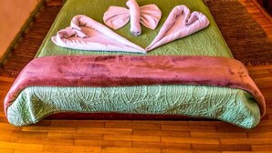 Una cama con cabecera de madera, dos lámparas de noche y una colcha verde.