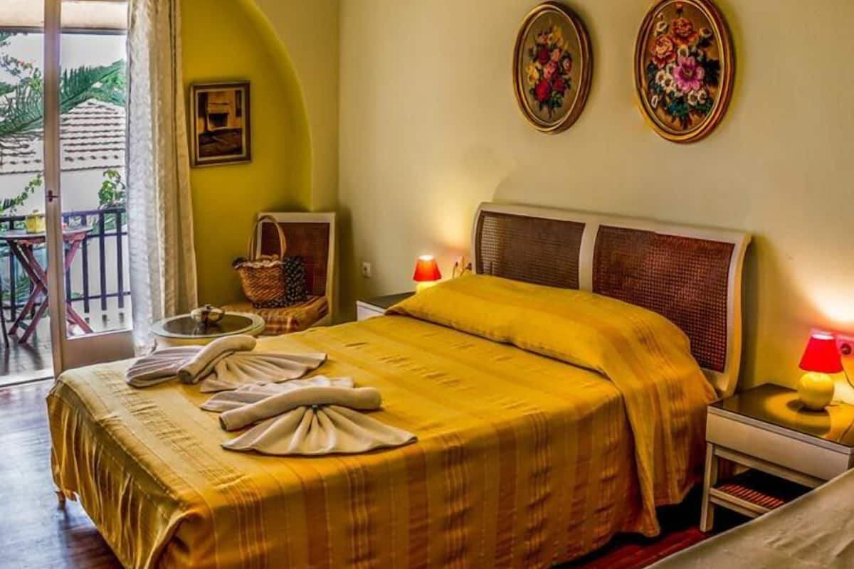 A hotel room with a bed, a balcony, and two wall-mounted flower paintings.