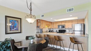 Una cocina moderna con armarios de madera, electrodomésticos de acero inoxidable y una isla central con taburetes de bar.