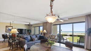 Un salón amplio con una gran mesa de vidrio, asientos cómodos y vistas a la playa.