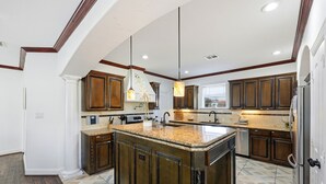 Un'ampia cucina con una grande isola, mobili in legno e luci a sospensione.