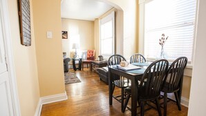 A dining area with a wooden table and chairs, a lamp, and a vase on the windowsill. - Charming & Historic Babs Condo on Hip Strip- Missoula's Best! (Missoula)
