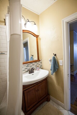 A bathroom with a white sink, wooden vanity, and a mirror with lights.