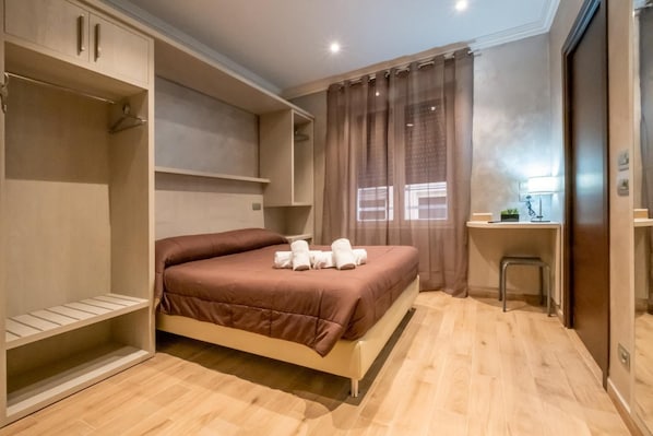 A bedroom with a bed, a desk, and a wardrobe.