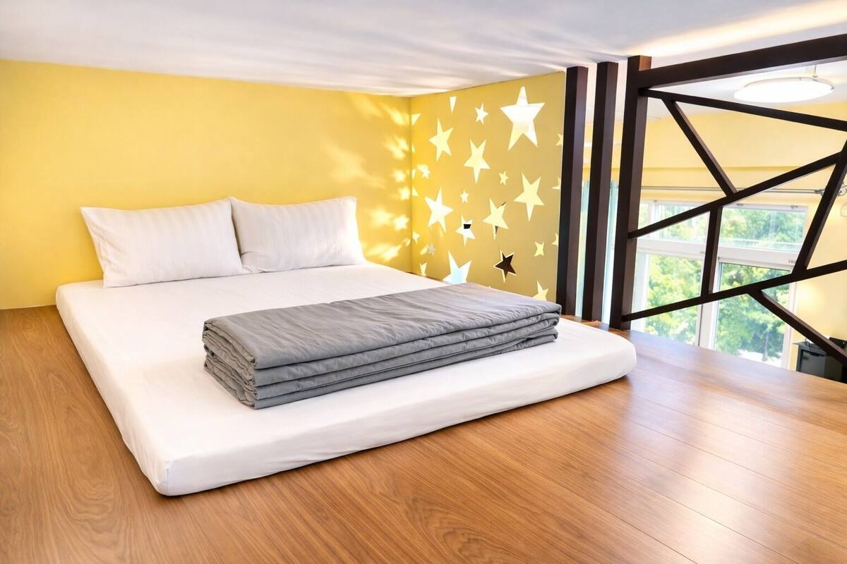 A modern bedroom with a bed, a star-patterned wall, and a view through large windows.