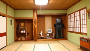 Une pièce de style japonais traditionnel, avec un sol recouvert de tatamis, un téléviseur, un radiateur et un paravent en papier de riz (shoji).