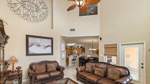A spacious living room with two brown leather sofas, a wooden coffee table, and a dining area with a kitchen in the background. - Spacious Family Retreat | Pool Access & Beach Nearby (Corpus Christi)