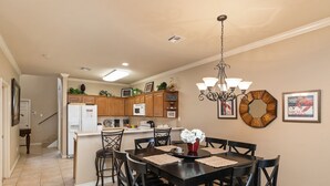 A dining area with a table set for four, surrounded by chairs, a chandelier, and a decorative mirror on the wall. - Spacious Family Retreat | Pool Access & Beach Nearby (Corpus Christi)