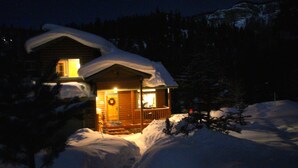Una cabana de fusta amb un porxo, envoltada de neu.