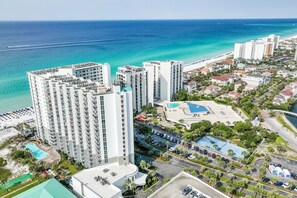 A high-rise hotel with multiple floors, a swimming pool, and a beach view. - On the Beach - First responders, Medical/Military discounts (destin)