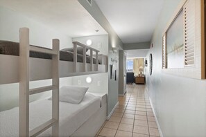 A narrow hallway with bunk beds on one side and a seating area on the other. - On the Beach - First responders, Medical/Military discounts (destin)