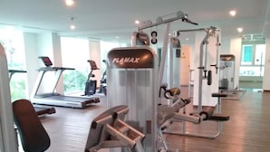 A gym with treadmills, weight machines, and a mirrored wall. - Amazon Residence Condo by MaiNot (Pattaya)