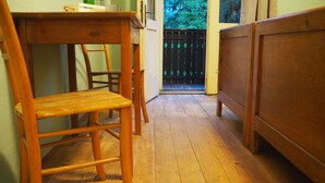 A narrow hallway with wooden flooring, a wooden chair, a small table, and a wooden bed. - Vila Koman (Jezersko)