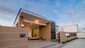 Un edificio moderno con entrada a cuadros, un cartel con dirección visible y un acceso con portón.