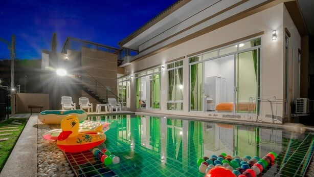 Una casa moderna con piscina, mobiliario exterior y una escalera que lleva al piso superior.
