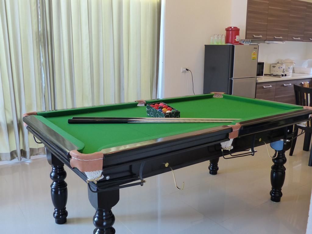 A pool table in a room with a kitchen in the background.