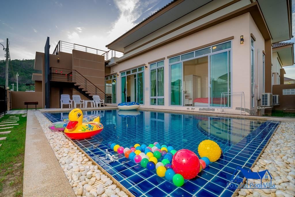 A swimming pool with inflatable toys and a tiled deck.
