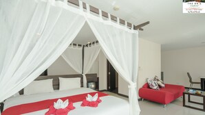 Een hotelkamer met een groot bed, een rode bank en een televisie.