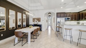 A modern kitchen with dark wooden cabinets, stainless steel appliances, and a central island with stools. - Walk to Vanderbilt Beach, Pets, 2 Mstrs w Kings beds, htd pool, bikes, BBQ (North Naples)