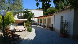 A courtyard with a paved walkway, outdoor seating, and potted plants. - Agriturismo Valle Dei Gelsi (Peschici)