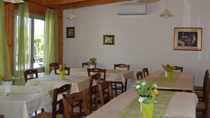 A dining area with wooden tables and chairs, green curtains, and hanging pendant lights. - Agriturismo Valle Dei Gelsi (Peschici)