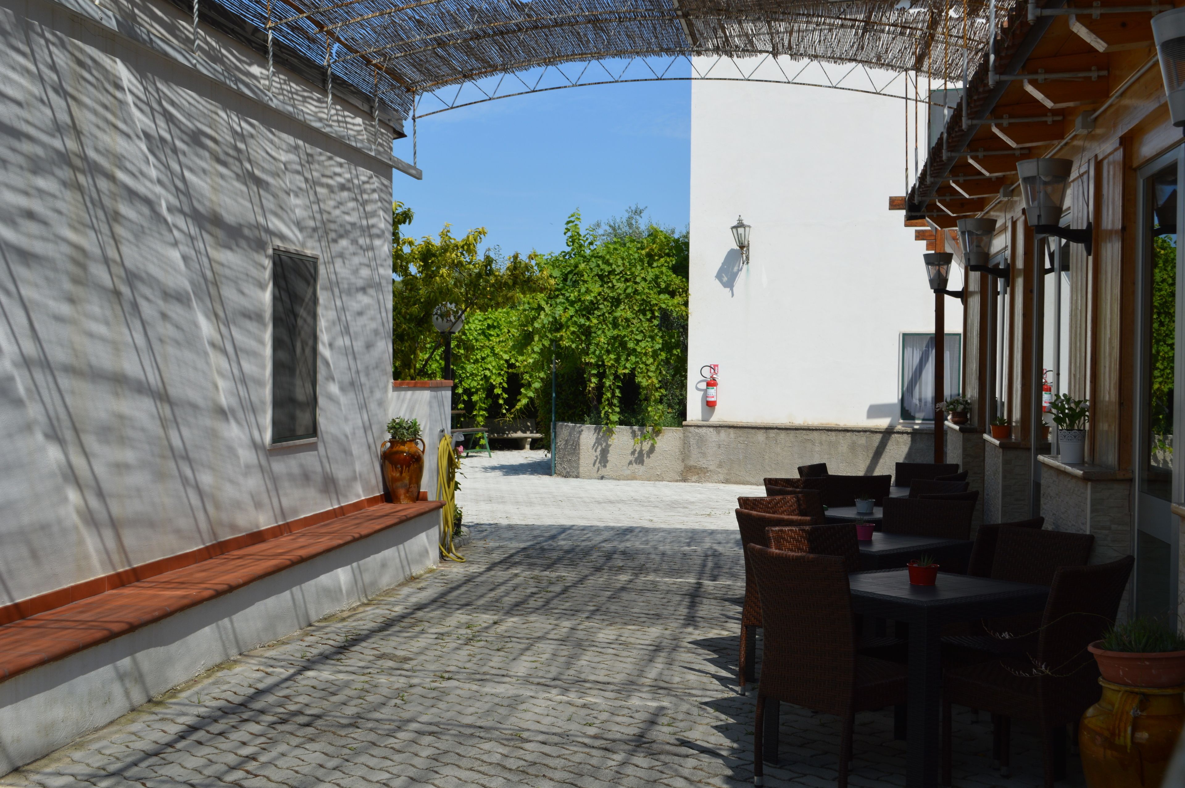 An outdoor patio area with stone flooring, wicker furniture, and potted plants.