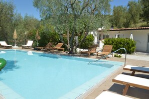 A swimming pool with lounge chairs and umbrellas, surrounded by trees and a building. - Agriturismo Valle Dei Gelsi (Peschici)