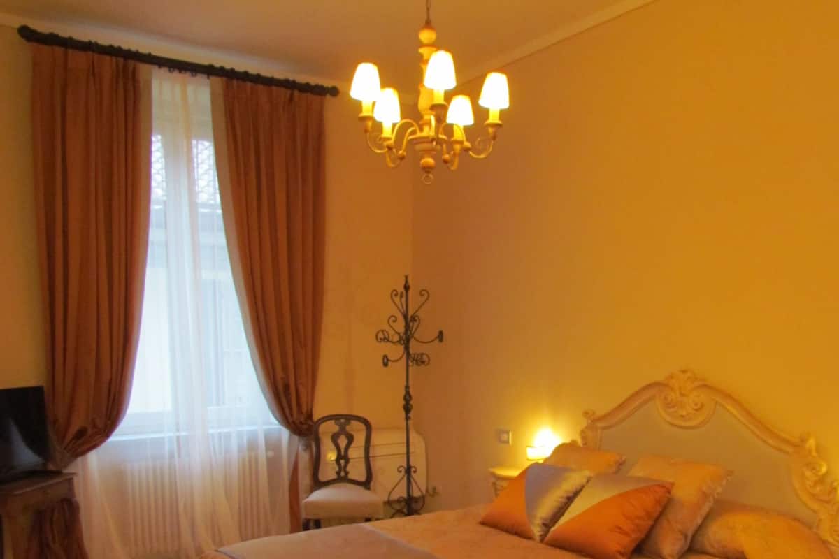 Ein geräumiges Schlafzimmer mit einem großen Bett, einer Deckenleuchte, einem Sessel und einer Stehlampe.