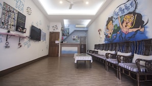 A room with a long bench seating area, a table with a tablecloth, and a mural on the wall. - SouthSea B&B (Liuqiu)
